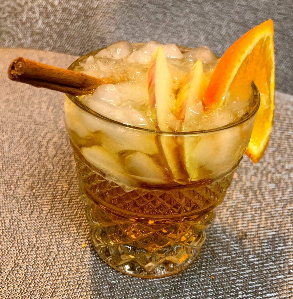 Garnishing a Fall Beverage with Orange and Apple Slices and Cinnamon Stick