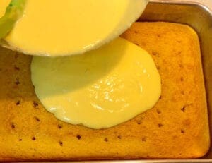 Pouring Vanilla Puddling over the Yellow Cake with Holes in it