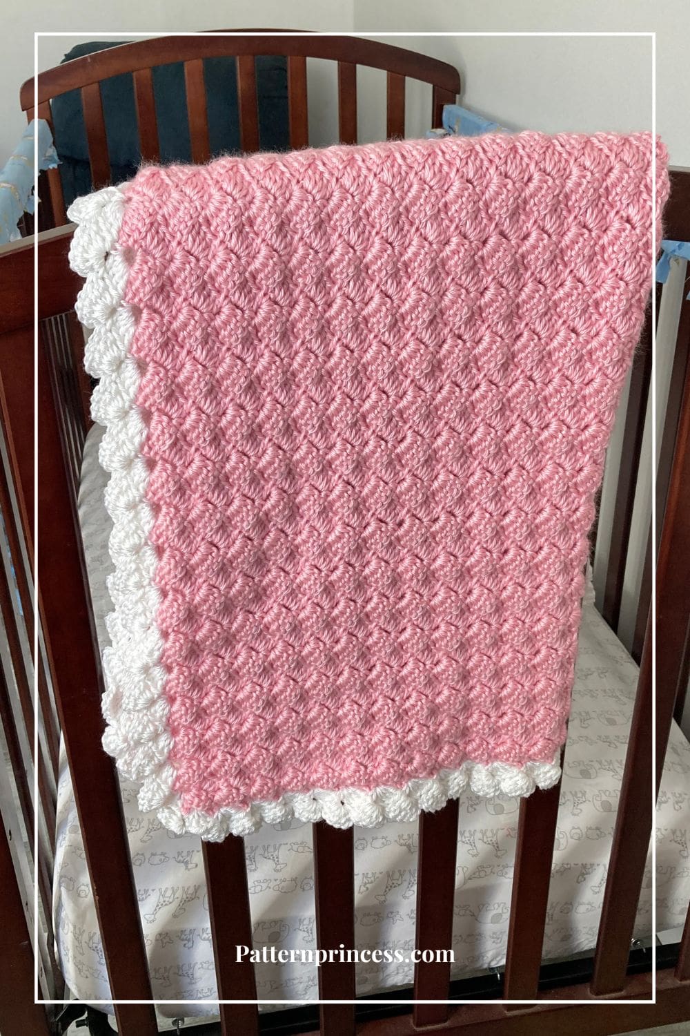 Pink and White Baby Blanket on Crib Rail