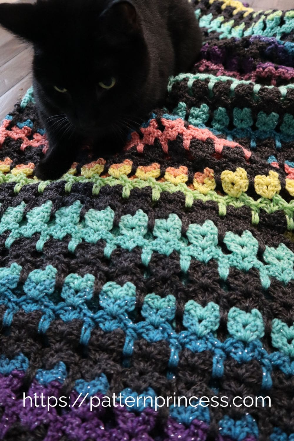 Close up of cat stitch with black cat enjoying blanket